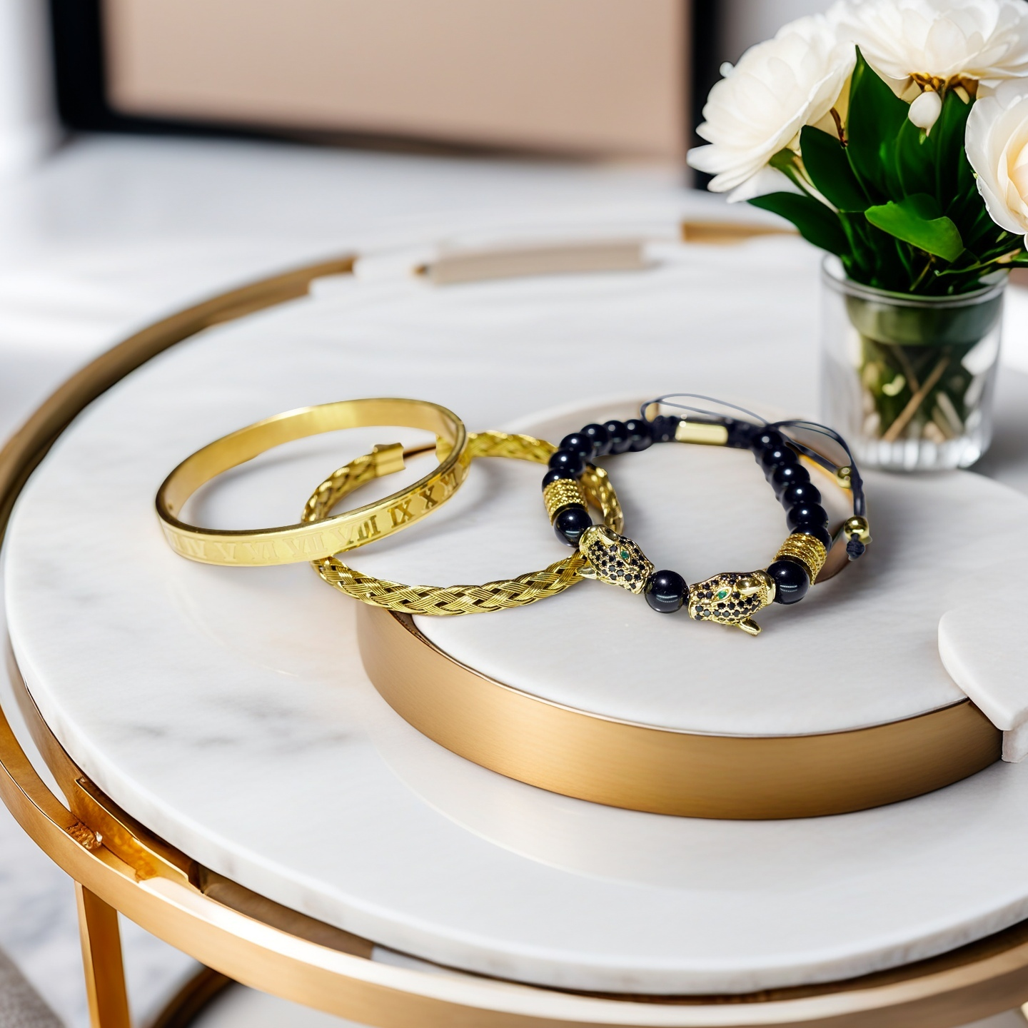 A round marble table with gold trim showcases the TAOÉ Gothic Black Panther Braid + Golden Steel Numeral Bracelet Panther Set-Metal by Five Elements Series, accompanied by a small vase of white flowers.